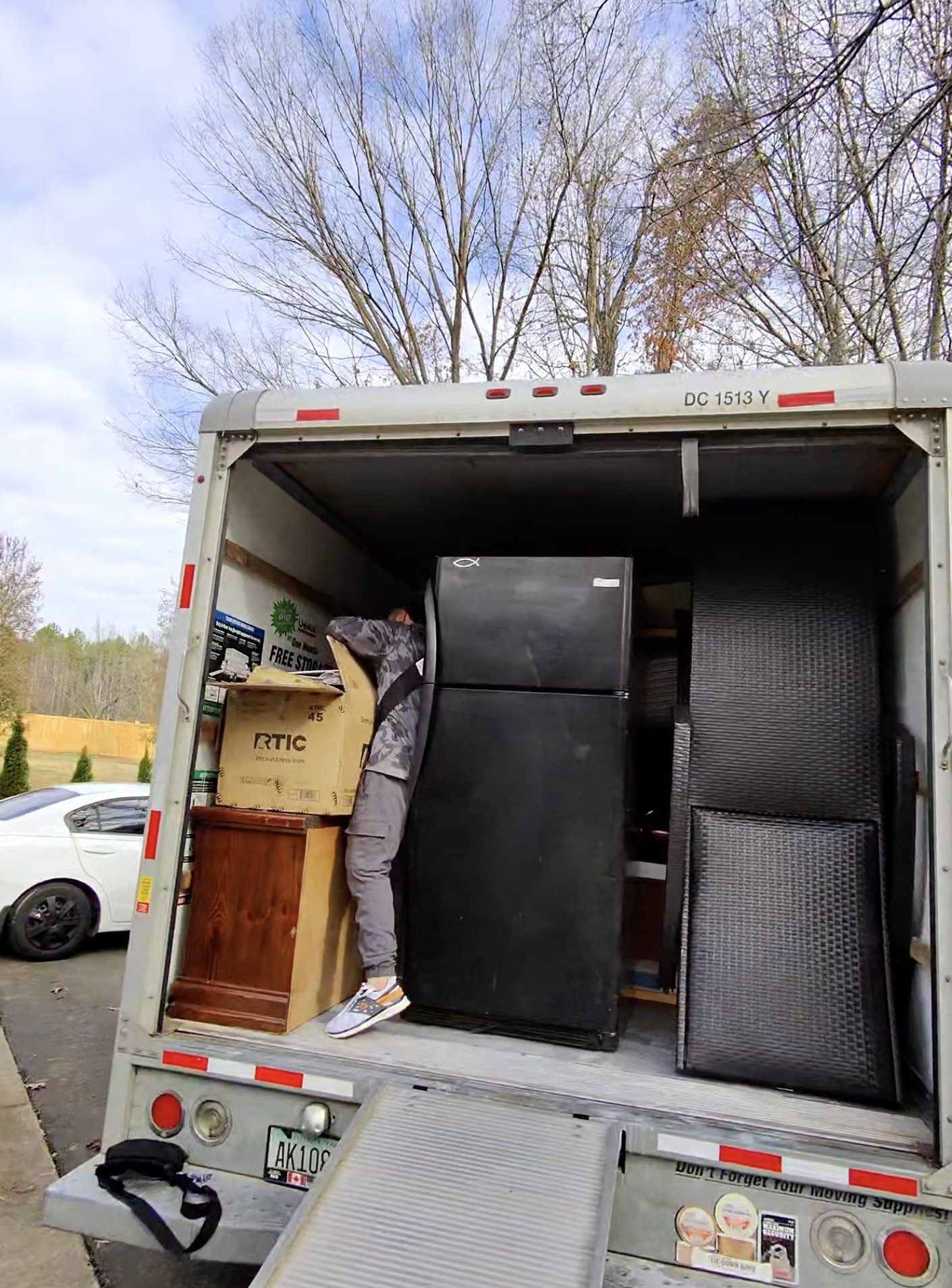 Crew member loading a refrigerator and furniture into the moving truck